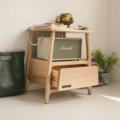 an old fashioned radio sitting on top of a wooden stand next to a potted plant