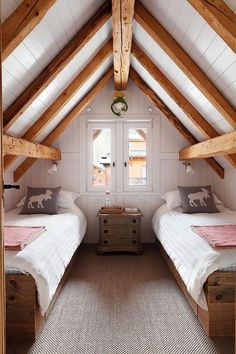 two beds in a room with white walls and wooden beams on the ceiling, one is made from wood