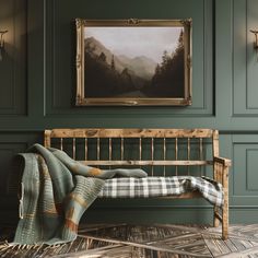 a painting hangs on the wall next to a wooden bench with a plaid blanket draped over it