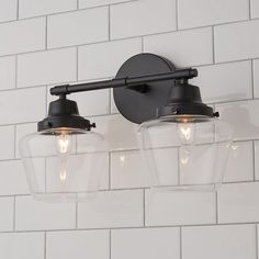 two lights are attached to the wall in front of a white brick wall with black fixtures