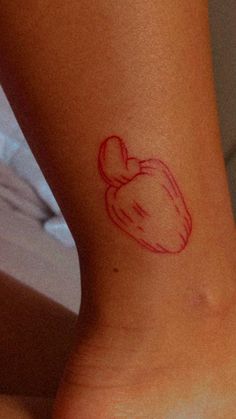 a small tattoo on the ankle of a woman's foot with a red apple