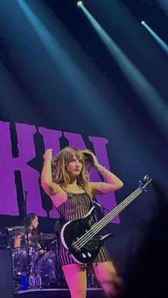 a woman standing on top of a stage holding a guitar