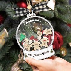 someone is holding up a christmas ornament in front of a decorated christmas tree