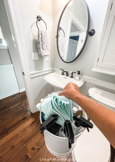 a person is cleaning the inside of a bucket in front of a sink and mirror