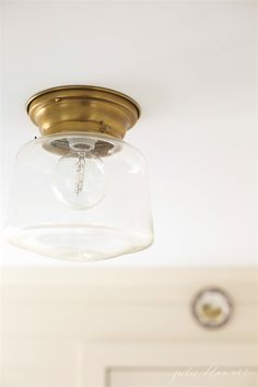 a light fixture with a glass jar on the bottom and a metal ring hanging from the ceiling