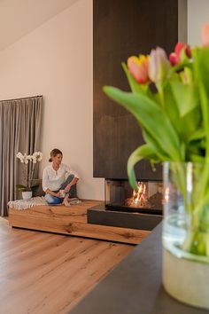 a woman sitting on a couch next to a fire place in a living room filled with furniture