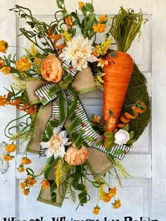 a wreath with carrots and flowers hanging on a door