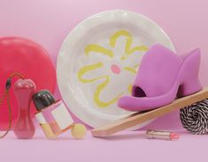 an assortment of items are displayed on a pink background, including a plate and lipstick