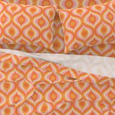 an orange and pink bed with two pillows on top of each other, next to a white pillow