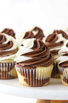 cupcakes with chocolate frosting and white icing on a cake platter