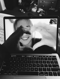 a laptop computer sitting on top of a bed next to a woman's face