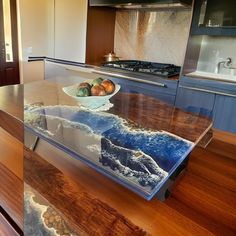 a bowl of fruit sitting on top of a glass table in the middle of a kitchen