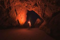 a person standing in the middle of a cave at night with a light on their head