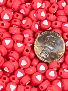 a penny sitting on top of red heart shaped beads