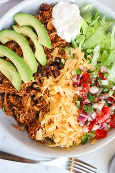 a white bowl filled with salad and avocado slices