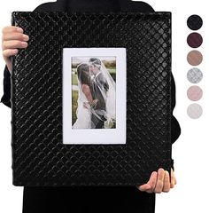 a person holding up a black photo frame with a wedding picture in it's center