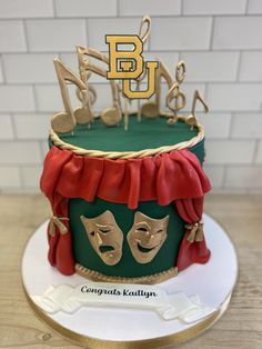 a green and gold cake with musical notes on top, topped by a red ribbon