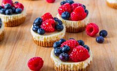 small cupcakes topped with fresh berries and blueberries on a cutting board, ready to be eaten