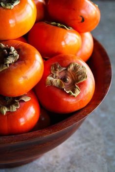 a wooden bowl filled with lots of ripe tomatoes