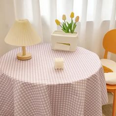 a table with a lamp on it next to a chair and a vase filled with tulips