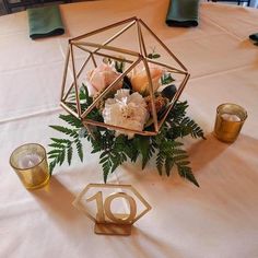 a centerpiece with flowers and candles on a white tableclothed table cloth in the shape of a octagon