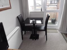 a small dining table and chairs in front of a window with a view of the street