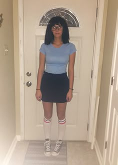 a woman standing in front of a door wearing knee high socks and a blue shirt