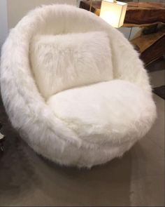 a large white chair sitting on top of a metal table next to a potted plant