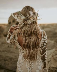 the back of a woman's head with long hair and flowers in her hair