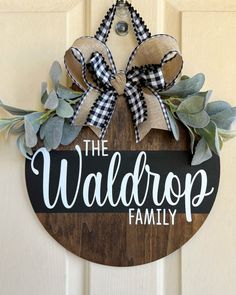 a wooden sign that says the waldrop family hanging on a door with greenery