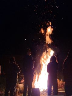 people standing around a fire pit at night