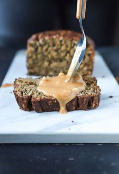 someone is spreading peanut butter on top of a loaf of bread that has been cut in half