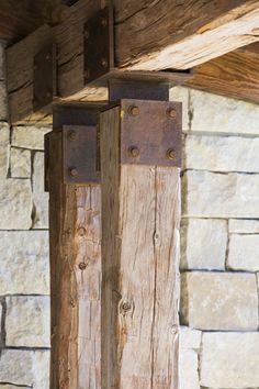 two wooden poles with metal rivets on them in front of a stone wall