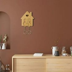 a wooden clock mounted to the side of a wall next to a table with cups on it