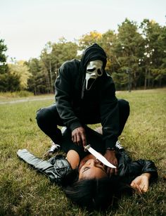 a person in a mask holding a knife on the ground