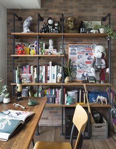 a wooden desk sitting next to a bookshelf filled with lots of books and toys