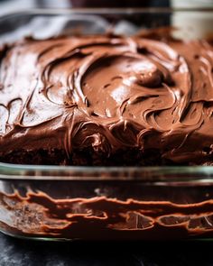 a chocolate cake with frosting in a glass dish