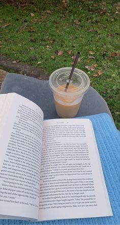 an open book sitting on top of a blue blanket next to a cup of coffee