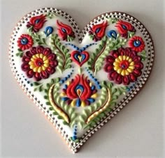 a heart shaped cookie decorated with flowers and leaves