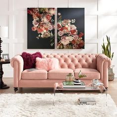 a living room with two paintings on the wall and a pink couch in front of it