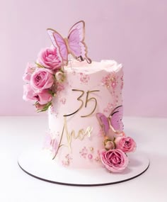 a pink birthday cake decorated with flowers and butterflies