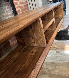 a black and white cat laying on the floor next to a wooden shelf with bookshelves