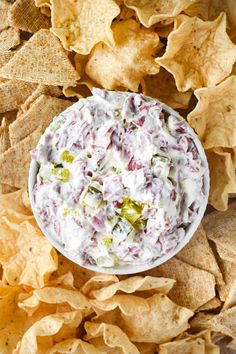 a white bowl filled with dip surrounded by tortilla chips