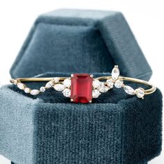 a close up of a ring with a red stone in the middle and white stones on it