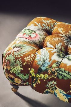 an upholstered foot stool with flowers on it