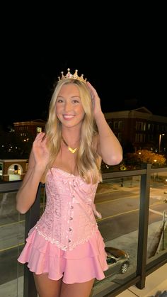 a woman in a pink corset posing on a balcony with her hands behind her head