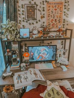 a computer desk topped with lots of clutter next to a wall covered in pictures