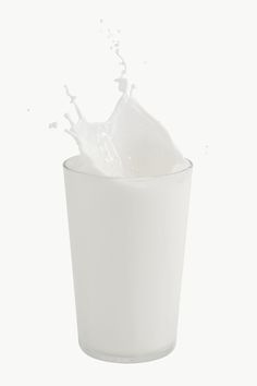 a glass filled with milk on top of a white table