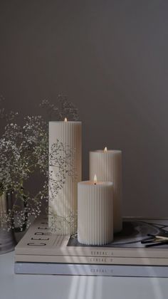 three white candles sitting on top of a book