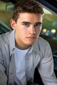 a young man sitting in the back seat of a car with his hand on his hip